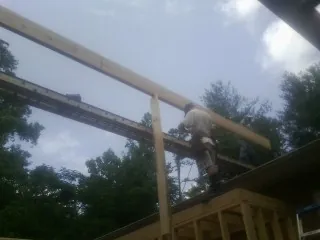 Carpenter setting a ridge beam over a new addition frame — Ice Dam Removal by Roofing Brothers in Maple City