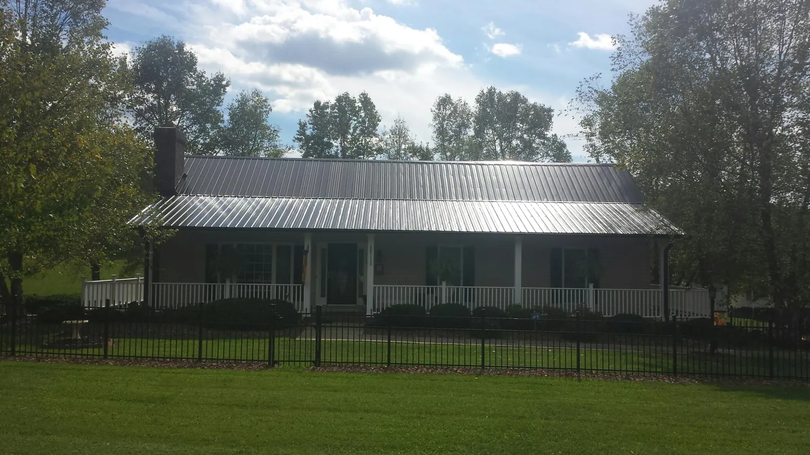Gray metal roof on a brick ranch with a full width front porch — Gutter Guard Installation work by our crew in Maple City